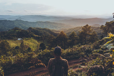 Rear view of people looking at mountains against sky