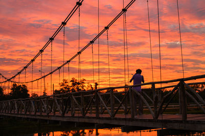 Silhouette man on bridge against sky during sunset