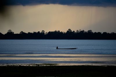 Silhouette boat in lake against sky during sunset