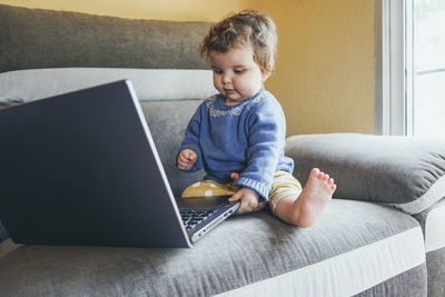 Boy looking away while sitting on sofa at home