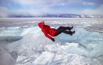 Full length of person jumping on frozen river during sunny day