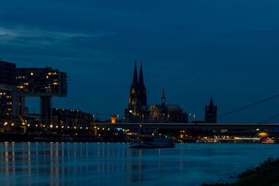 Ship in river by illuminated buildings at night