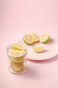 Fresh tasty lemon and lime citrus fruits slices on pink background