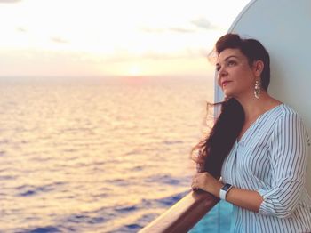 Beautiful woman looking up on boat in sea during sunset