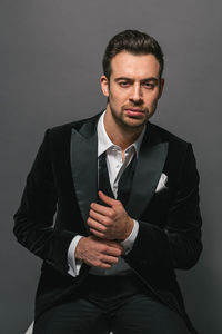 Portrait of young man standing against gray background