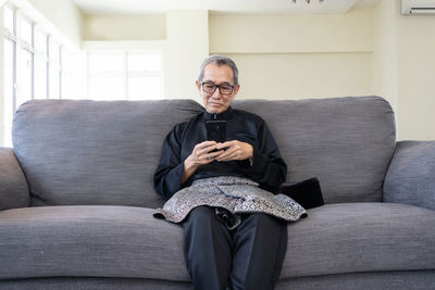 Portrait of man sitting on sofa at home