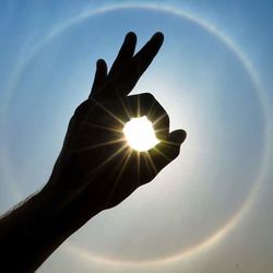 Low angle view of sun shining through clouds