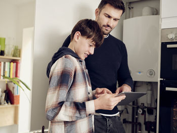 Son and father on a digital tablet checking boiler for energy saving at home