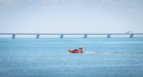 People on boat sailing in sea against sky