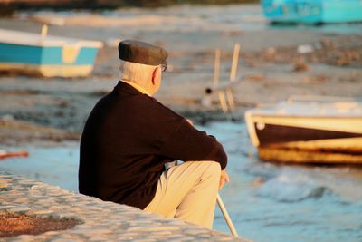 Rear view of man sitting on coast