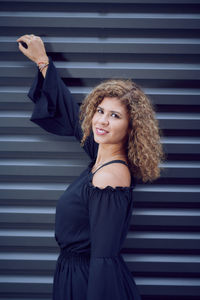 Portrait of a smiling young woman standing against wall