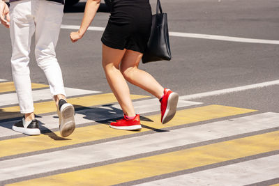 Low section of women walking on road