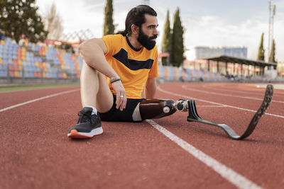 Athlete with prosthetic leg sitting on running track