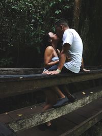 Couple kissing on footbridge in forest