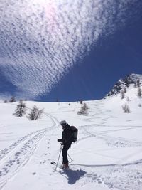 Man skiing on snow covered land against sky