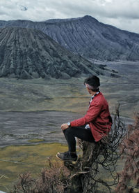 Man sitting on rock looking at mountains