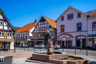 Statue by buildings against sky in city