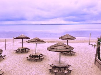 Deck chairs on beach against sky
