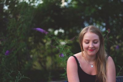 Young woman smiling against trees