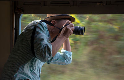 Side view of man photographing in train 