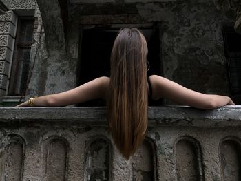 Rear view of woman sitting against building