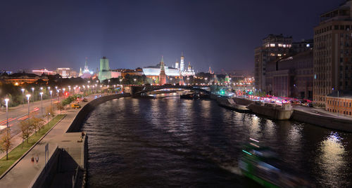 Illuminated bridge over river in city at night