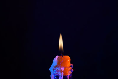 Close-up of lit candle against black background