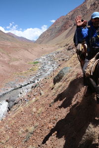 People riding on mountain road against sky