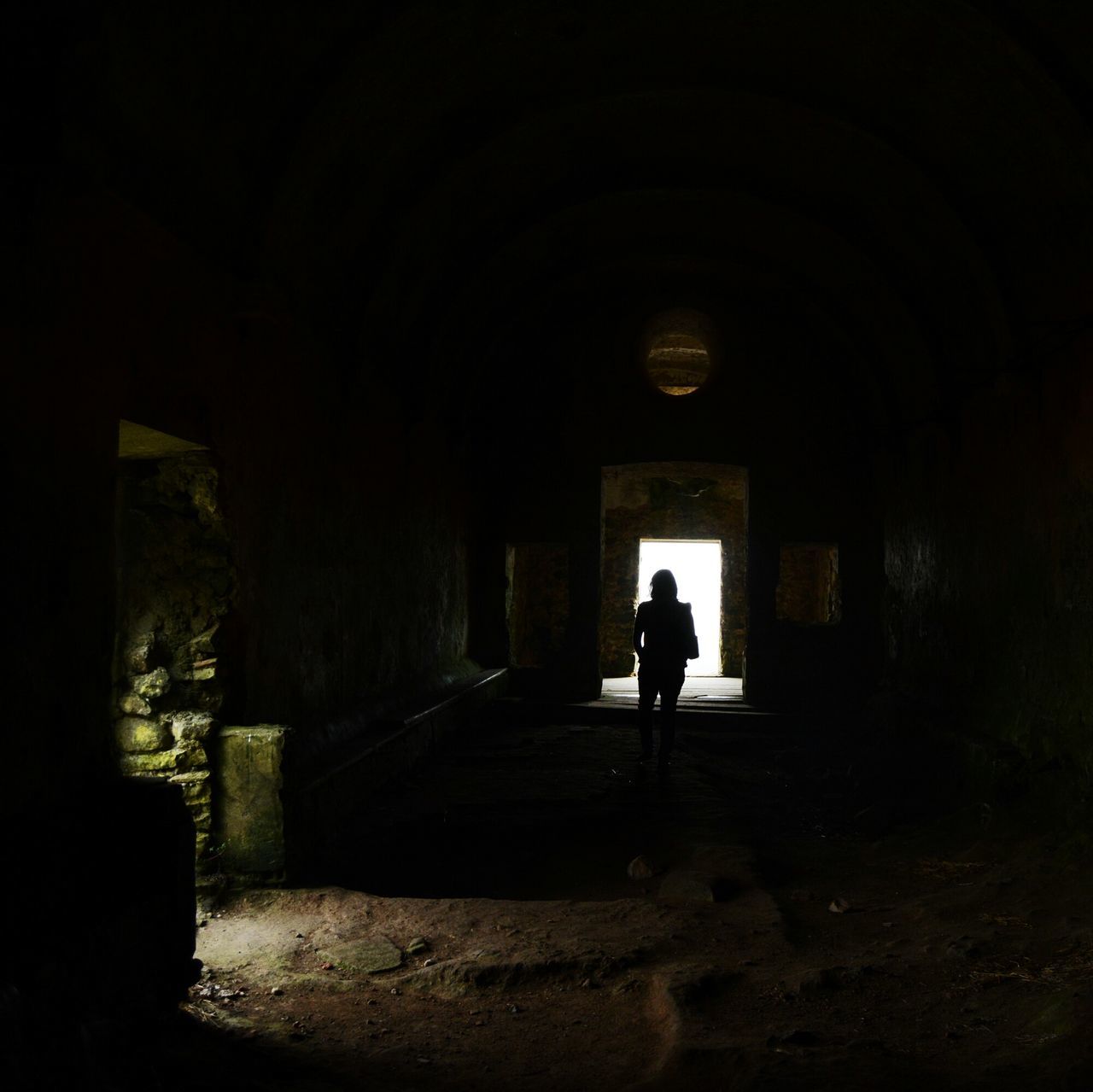 indoors, architecture, full length, arch, tunnel, built structure, men, silhouette, rear view, walking, lifestyles, dark, archway, the way forward, abandoned, standing, wall - building feature, leisure activity