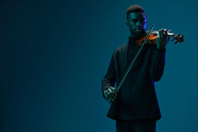 Young man with guitar against blue background