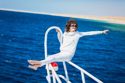 Woman relaxing on the nose of the yacht at a sunny summer day at sea