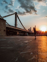Man on bridge against sky during sunset