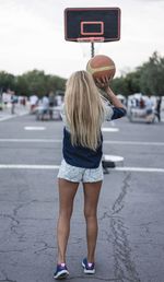 Rear view of young woman playing basketball