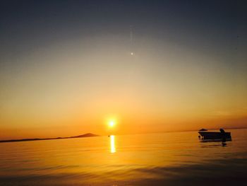 Silhouette of boat sailing in sea during sunset