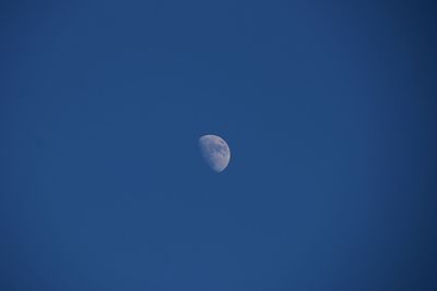 Low angle view of moon against blue sky