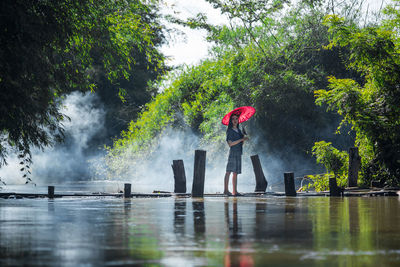 Man working in lake against trees