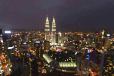 Defocused image of illuminated city against sky at night