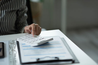 Midsection of businesswoman using calculator