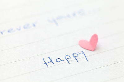 Close-up of happy text by heart shape on paper