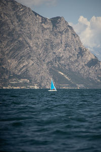 Sailboat sailing on sea against mountain