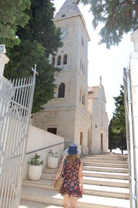 Rear view of woman walking on staircase against building