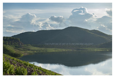 Scenic view of lake by mountains against sky