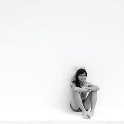 Portrait of teenage girl sitting against white background