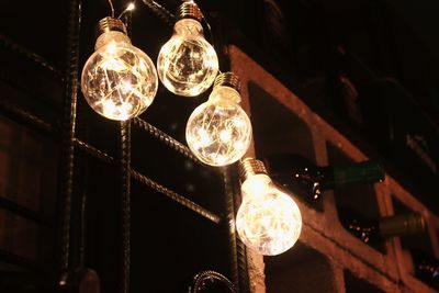 Low angle view of illuminated light bulbs hanging from ceiling