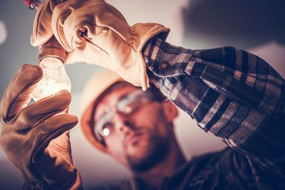 Close-up of man holding illuminated light bulb