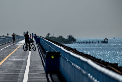 People walking on pier against clear sky