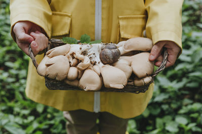Girl standing with basket of mushrooms in forest