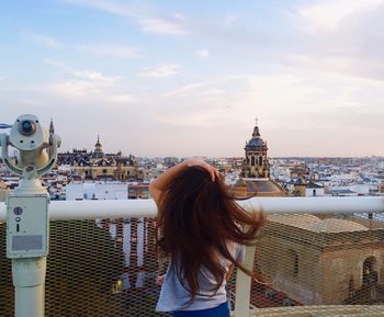 Rear view of woman looking at cityscape during sunset