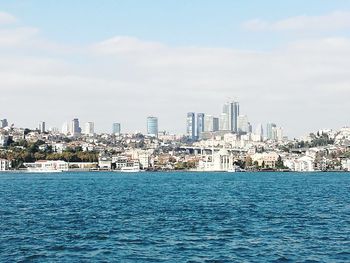 Sea by cityscape against sky