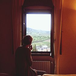 Rear view of women looking outside window